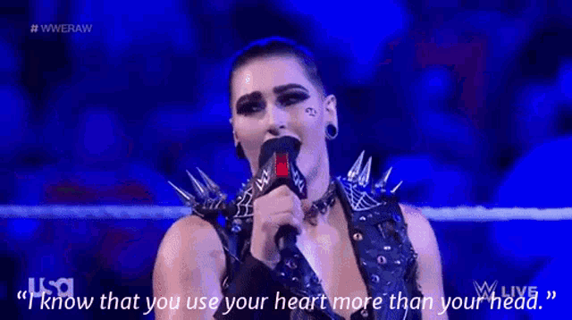 a woman is speaking into a microphone with the words " i know that you use your heart more than your head " behind her