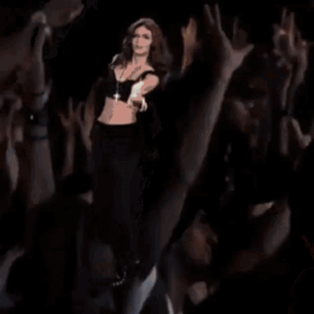 a woman is dancing on a stage in front of a crowd .