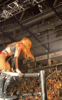 a female wrestler is jumping over a rope in front of a crowd .