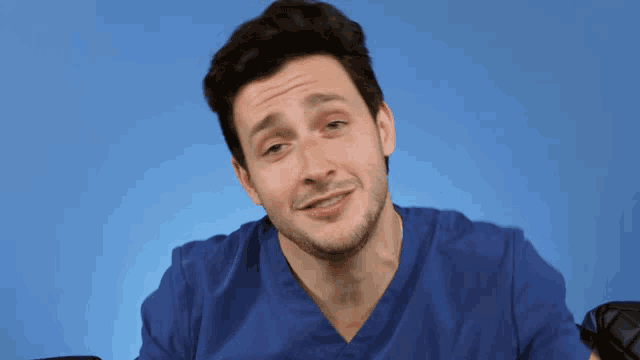 a man with a beard wearing a blue scrub top