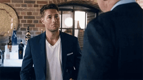 a man in a suit and a white shirt is shaking hands with another man .