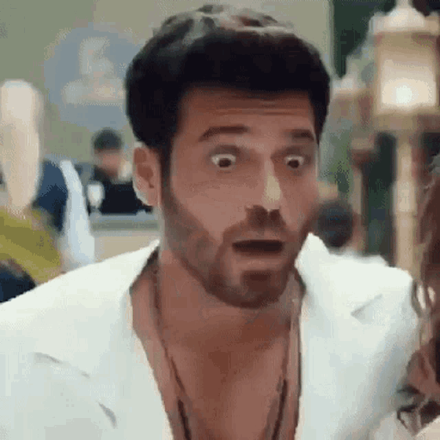 a man with a beard is making a surprised face while talking to a woman .