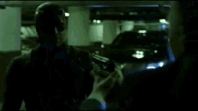 a man is laying on the ground in a dark room with a car behind him