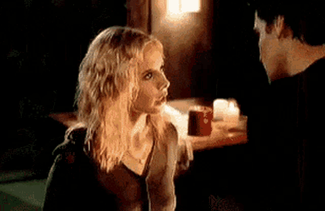 a man and a woman are sitting at a table with candles .