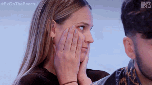 a woman covering her face with her hands while a man looks on with the hashtag #exonthe beach