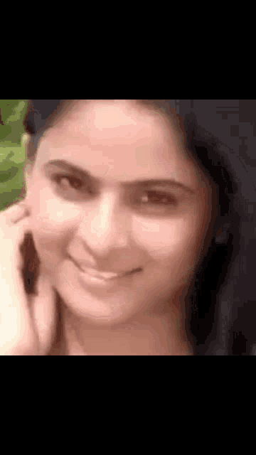 a close up of a woman 's face smiling and talking on a cell phone .