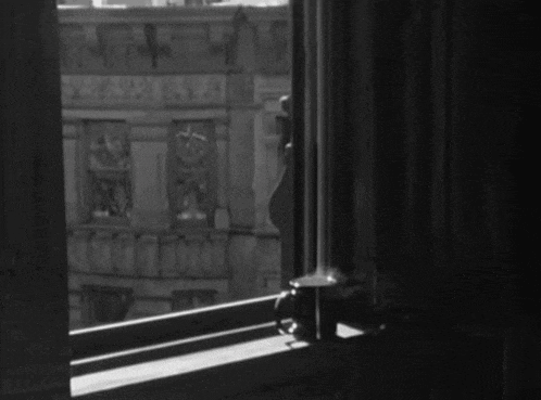 a black and white photo of a window with a cup on the sill
