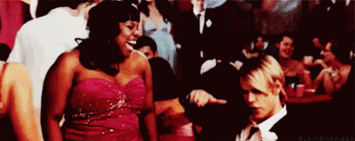 a woman in a red dress is dancing with a man in a tuxedo at a party .