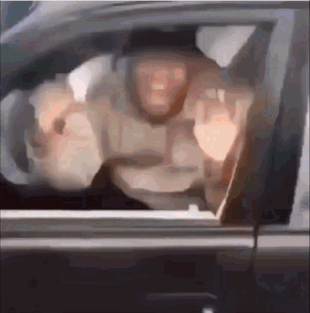 a man is giving the middle finger while driving a car .