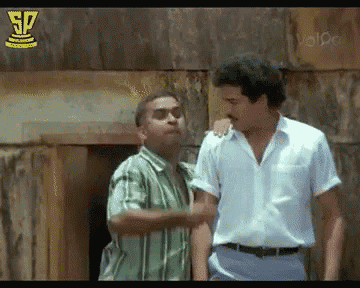 two men are standing next to each other in front of a building and one of them has his arm around the other 's shoulder .