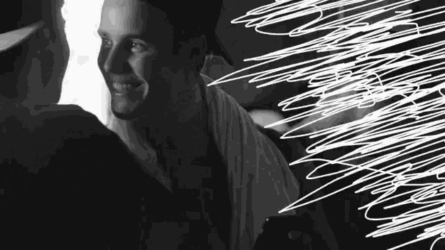 a black and white photo of a man smiling and holding a cell phone