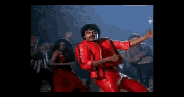 a man in a red leather jacket is dancing in front of a crowd of people .