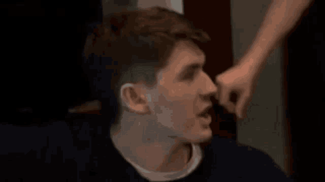 a man is being slapped in the face by another man .