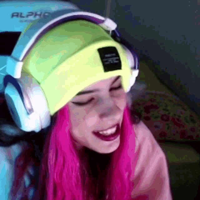 a girl with pink hair is wearing headphones and a neon yellow hat .