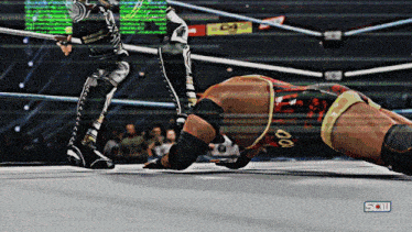 a wrestler with the number 00 on his shorts is laying on the ground in a wrestling ring