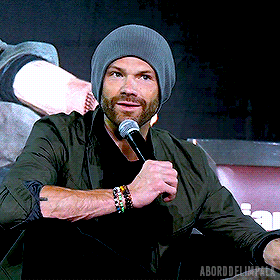 a man wearing a gray beanie is holding a microphone in his hand