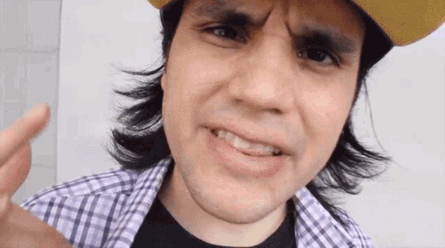 a close up of a man wearing a plaid shirt and a hat
