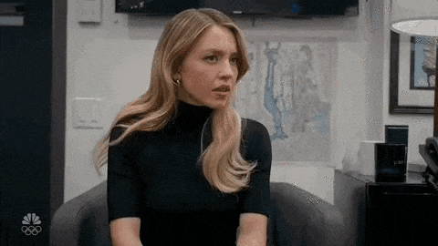 a woman in a black turtleneck is sitting in a chair in a room .
