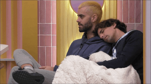two men laying next to each other on a bed