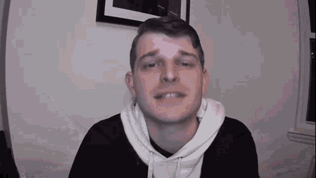 a man wearing a white hoodie is making a funny face .