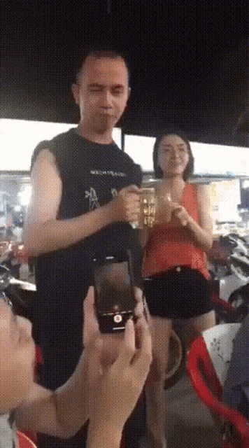 a man wearing a black shirt that says ' a ' on it is holding a beer