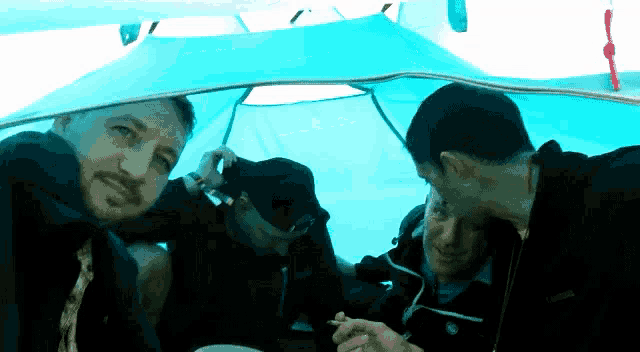 a man wearing a black jacket with the word columbia on it sits in a tent