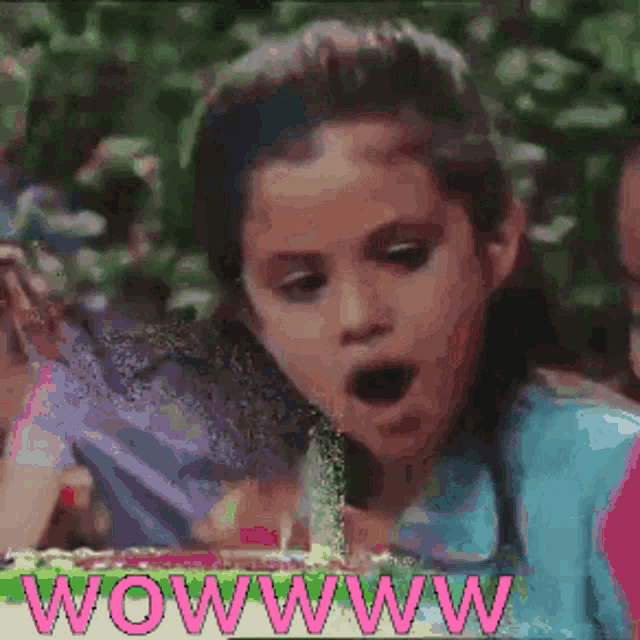 a little girl blowing out a candle with the words wowwww in pink letters