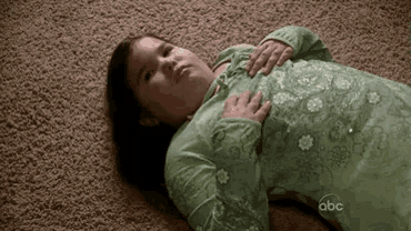 a little girl is laying on the floor holding her chest .