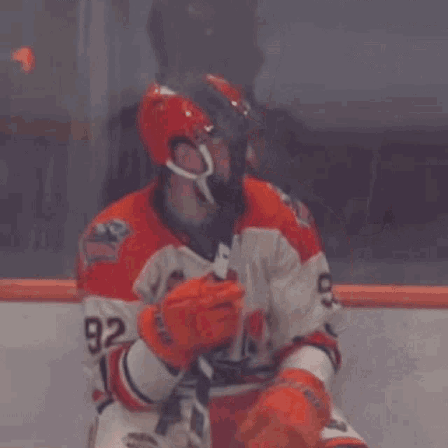 a hockey player wearing orange gloves with the word ccm on it