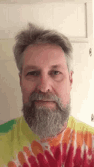 a man with a beard and mustache is wearing a tie dye t-shirt .