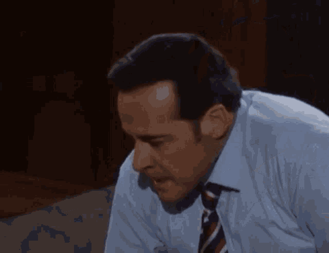 a man in a suit and tie is talking to another man in a white shirt .