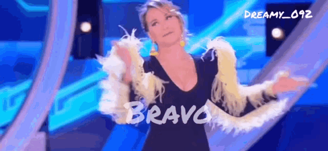 a woman in a black dress is dancing on a stage with the word bravo written on the bottom