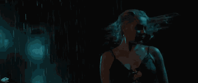 a woman is dancing in the rain in a dark room .