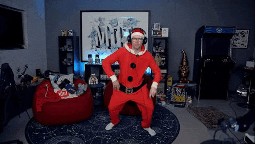 a man in a santa suit is dancing in a room with a bean bag chair with a pillow that says 1001