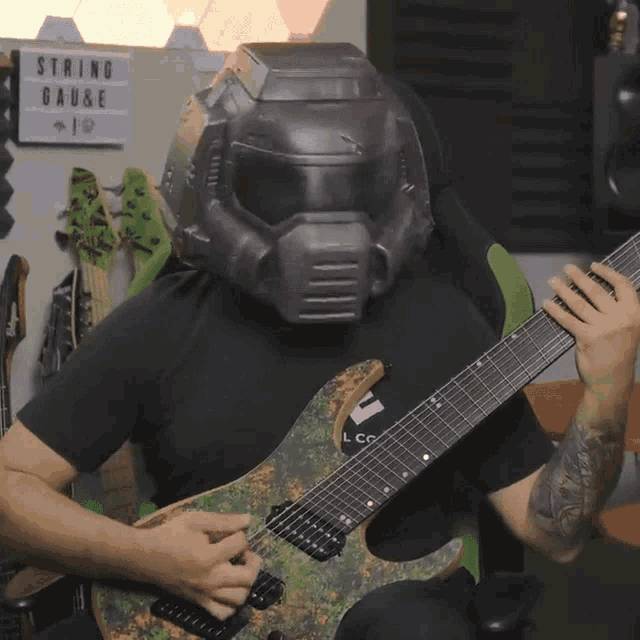 a man wearing a helmet playing a guitar in front of a string gauge sign