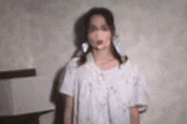 a woman in a white dress is standing in front of a wall in a room .
