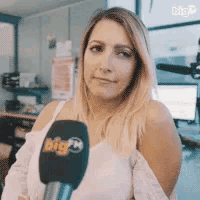 a woman is holding a microphone with big fm written on it .