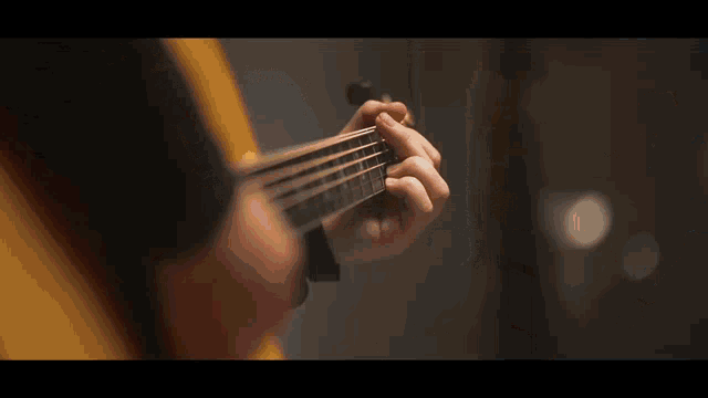 a person playing an acoustic guitar with a yellow jacket on