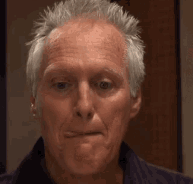 a man with gray hair is making a funny face .