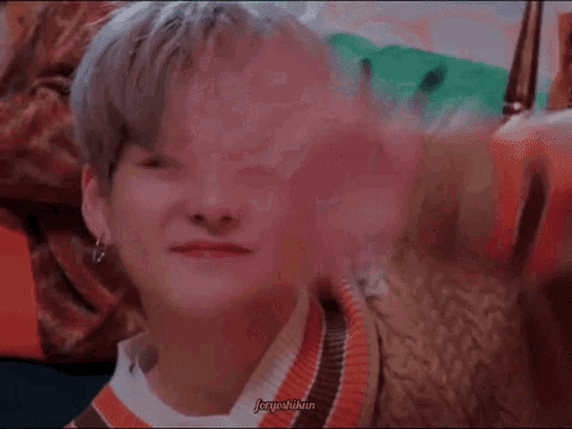 a close up of a person 's face with their eyes closed while wearing a sweater .
