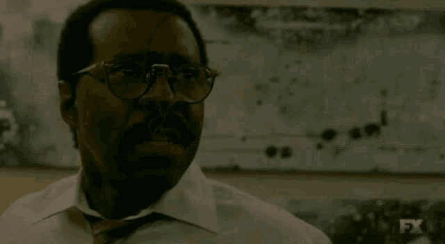 a man with glasses and a mustache is screaming with the word fuck above him
