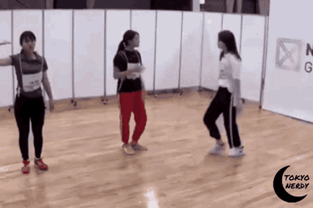 three girls are dancing on a wooden floor in a room with tokyo nerd written on the bottom
