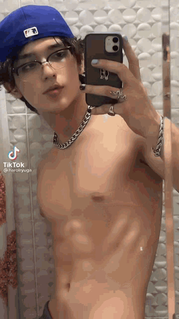 a shirtless young man is taking a selfie with his phone
