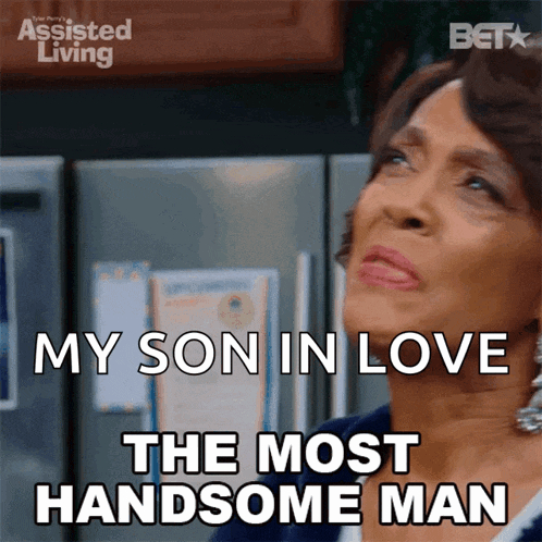 a woman says " my son in love the most handsome man " in front of a refrigerator