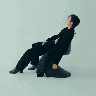 a man in a suit is laying on a chair with his legs crossed