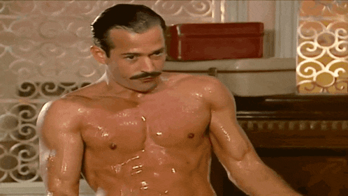 a shirtless man with a mustache is standing in a bathtub