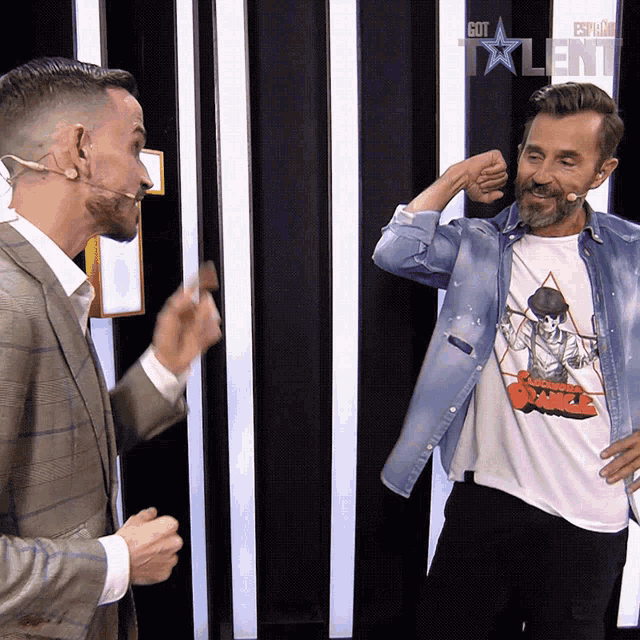 two men are standing in front of a wall that has got talent written on it