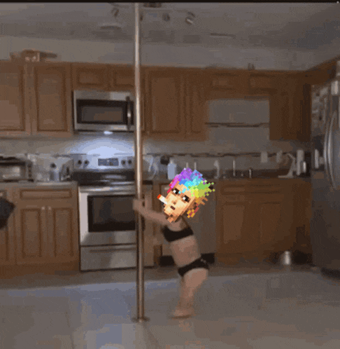 a little girl in a bikini is standing on a pole in the kitchen
