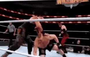two men are wrestling in a ring with a referee watching