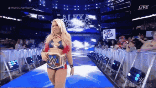 a female wrestler is walking down the aisle of a wrestling arena .